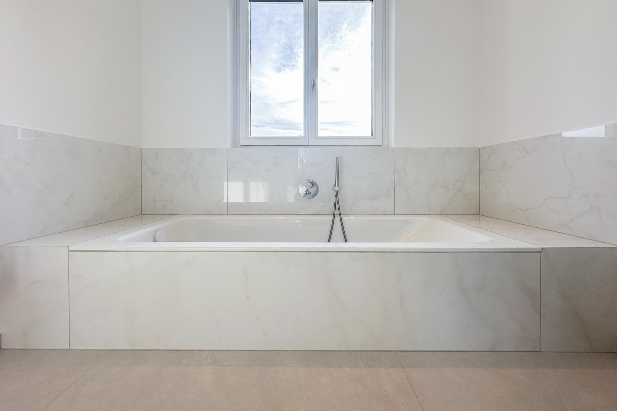 Luxury bathroom with limestone-look porcelain stoneware floor tiles and marble-look wall tiles